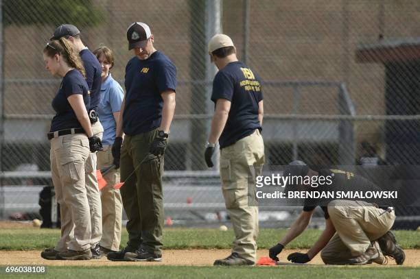 And other law enforcement officials inspect the crime scene after a shooting during a practice for the Republican congressional baseball game at...