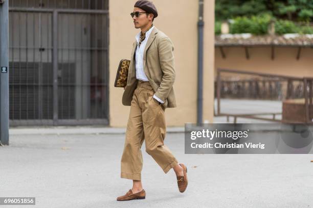 Guest wearing beret, brown pants, clutch, blazer is seen during Pitti Immagine Uomo 92. At Fortezza Da Basso on June 14, 2017 in Florence, Italy.