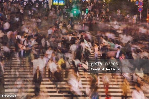 long exposure picture of people crossing in the scramble crossing of shibuya at night with nice motion effect. - shibuya crossing stock pictures, royalty-free photos & images