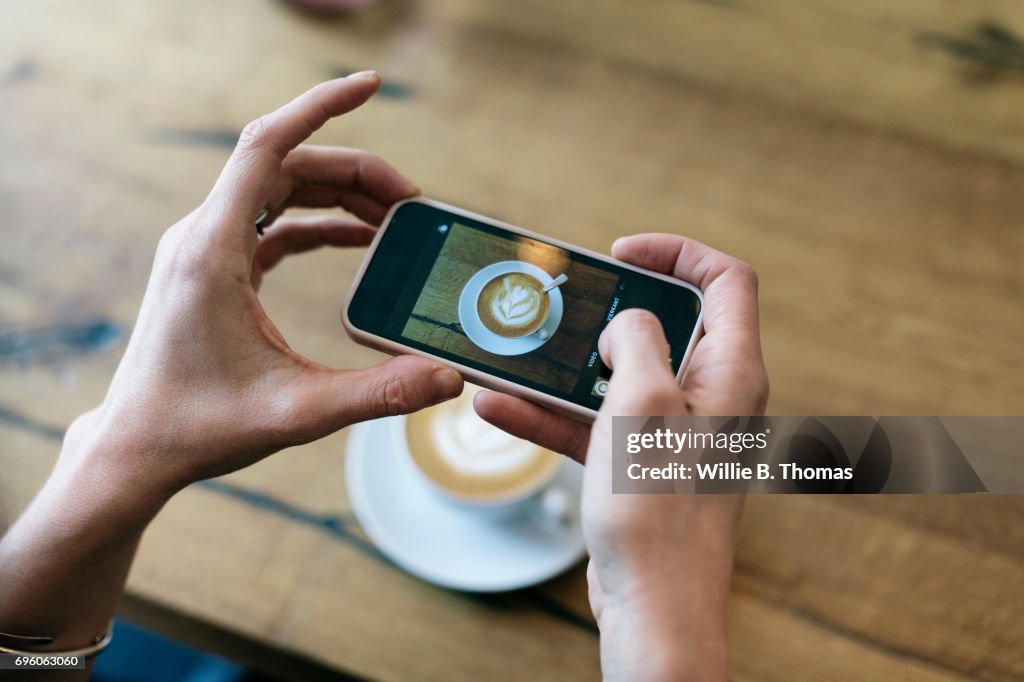 Woman Taking Photo Of Her Coffee At A Cafe