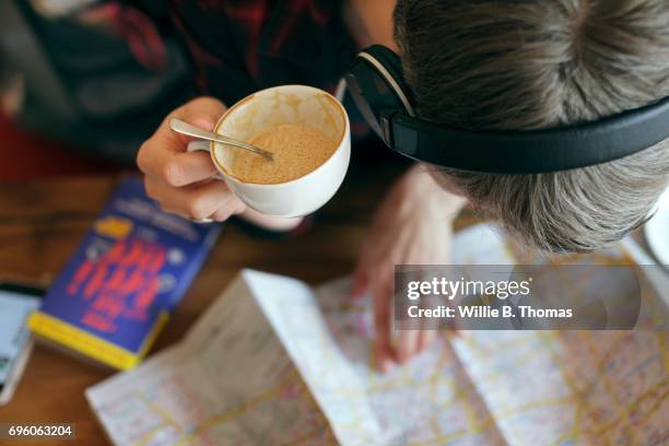 a backpacker reviews her route whilst sitting in a cafe - coffee spoon stock pictures, royalty-free photos & images