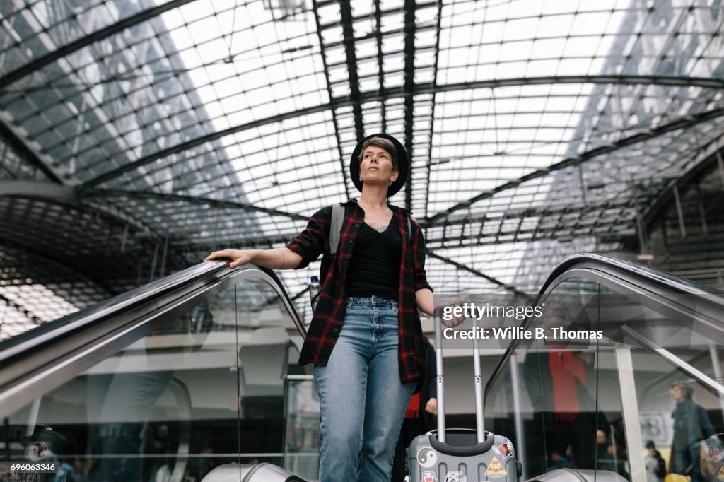 A Backpacker Using Escalator At A Train Station