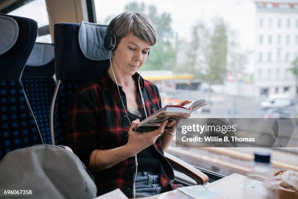 mature backpacker reading on train - project traveller stock pictures, royalty-free photos & images