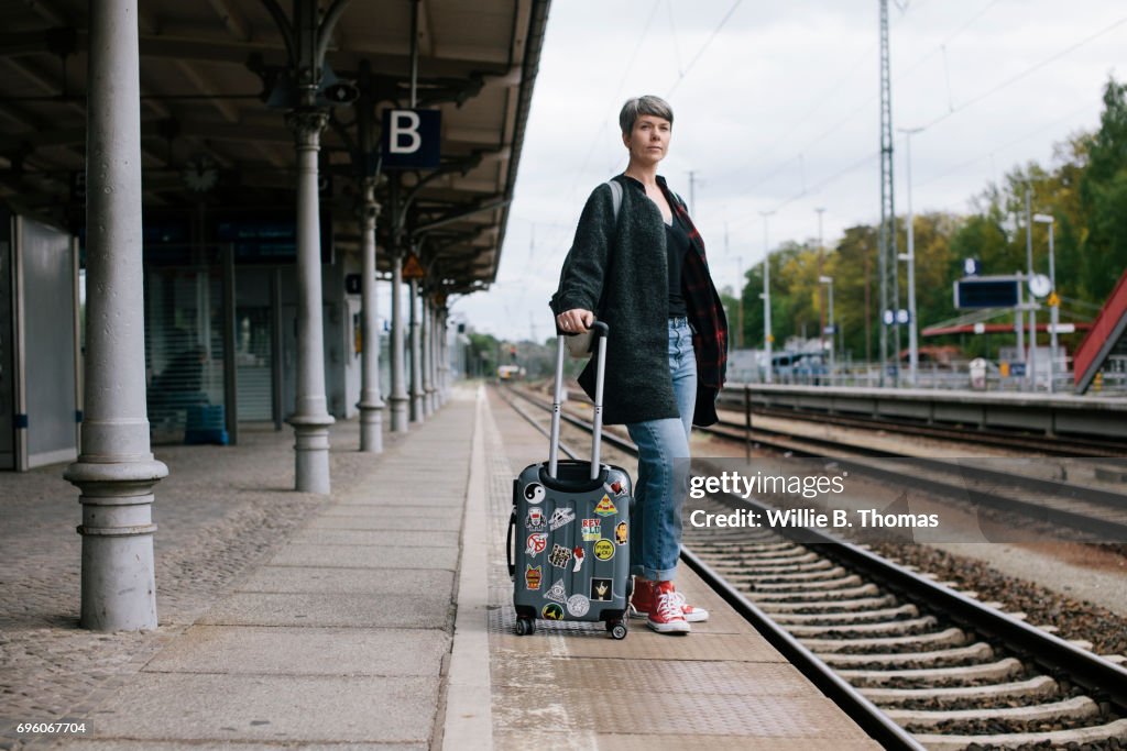 Mature Backpacker Waiting For Train On Station Platform