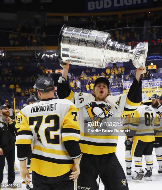Patric Hornqvist and Carl Hagelin of the Pittsburgh Penguins celebrate with the Stanley Cup following a victory over the Nashville Predators in Game...