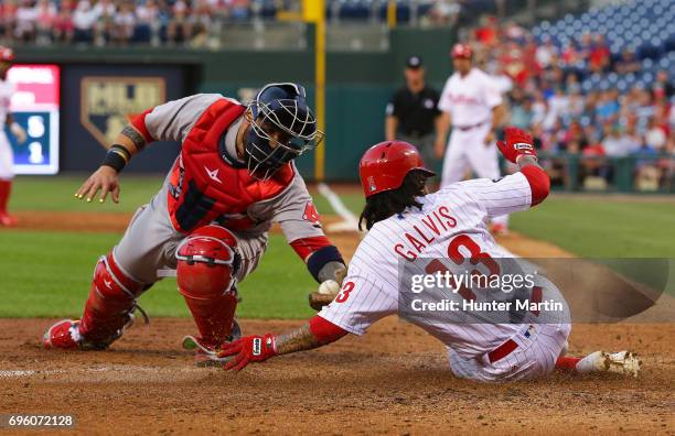 Freddy Galvis of the Philadelphia Phillies slides home safely in front of the tag by Sandy Leon of the Boston Red Sox in the third inning during a...