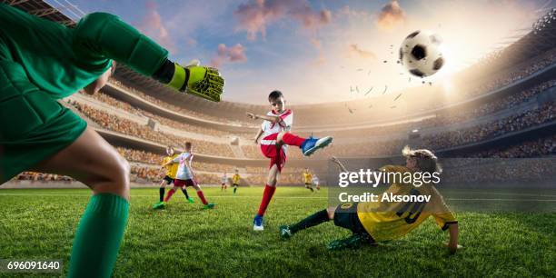 soccer kids players scoring a goal. goalkeeper tries to hit the ball - american football strip stock pictures, royalty-free photos & images