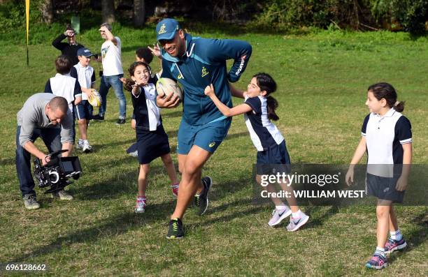 Australian rugby union player Lukhan Tui is swamped by school children after the team announcement in Sydney on June 15, 2017. Australia plays...