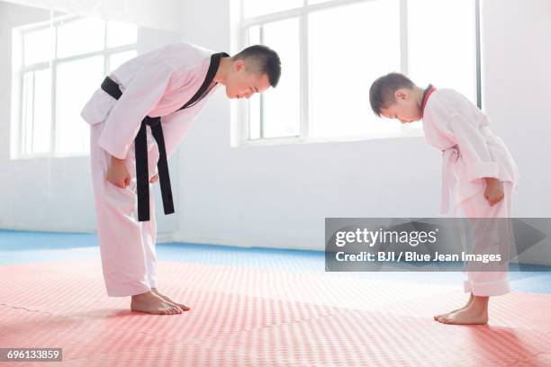 young instructor teaching boy tae kwon do - inchinarsi foto e immagini stock