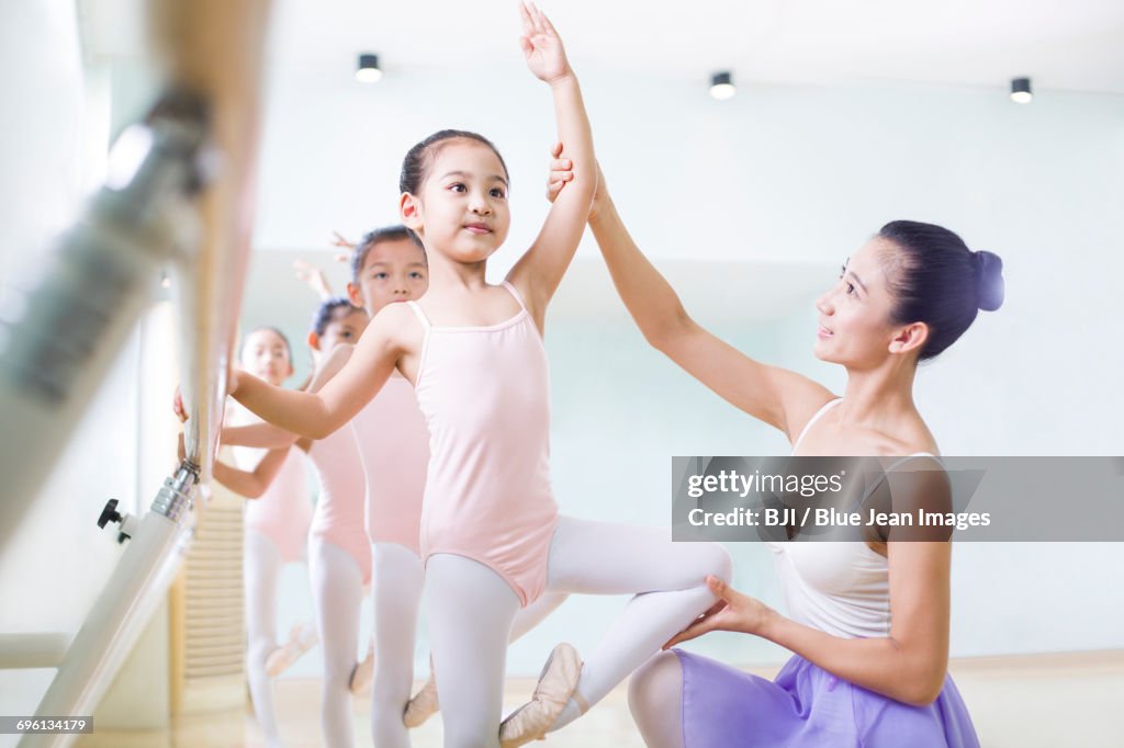 Young ballet instructor teaching girls in ballet studio