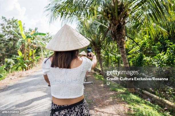 woman wearing traditional rice hat, taking selfie, tan phong island, vietnam - cultura orientale photos et images de collection