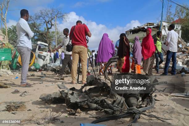 People inspect the site near the wreckage after bomb-laden vehicle attack by Al-Shabaab militants to a restaurant in Mogadishu, Somalia on June 15,...