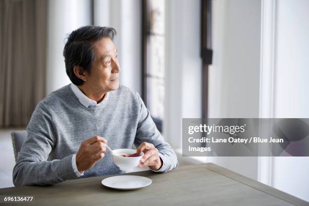 senior man eating nutritious porridge - soup on spoon imagens e fotografias de stock