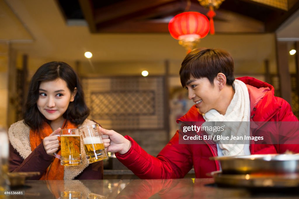 Young couple drinking beer in hotpot restaurant