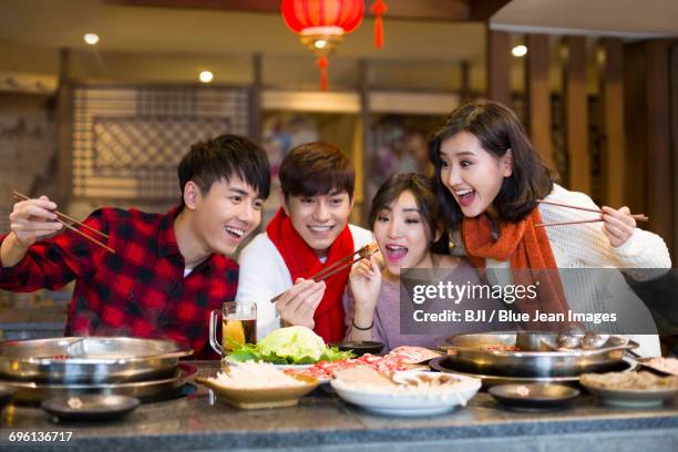 young friends having dinner in hotpot restaurant - chinese restaurant interior stock pictures, royalty-free photos & images