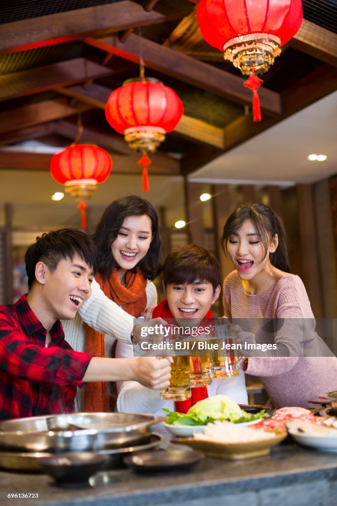 Young friends drinking beer in hotpot restaurant