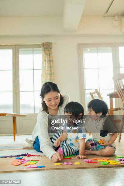 mother and two sons playing alphabet on carpet - 日本人　英語 ストックフォトと画像