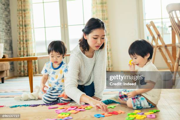 mother and sons playing alphabet toy on floor - 日本人　英語 ストックフォトと画像