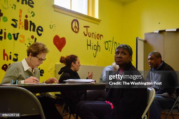 Frankie Sanders Munoz, 2nd from R, waits as volunteer Linda Flick, L, assists her in applying for an updated birth certificate as volunteers with...