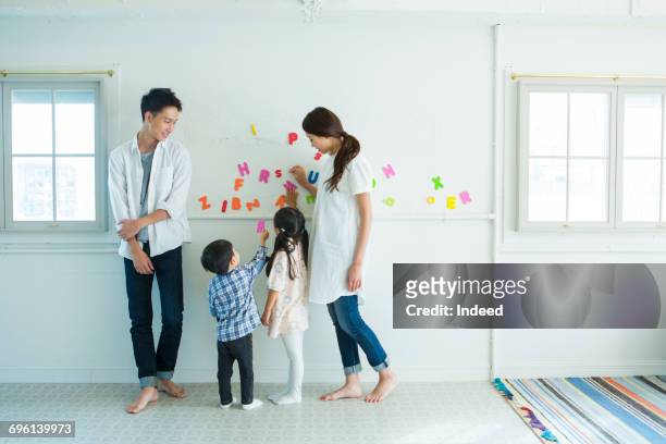 parents and children playing with alphabet by wall - 日本人　英語 ストックフォトと画像
