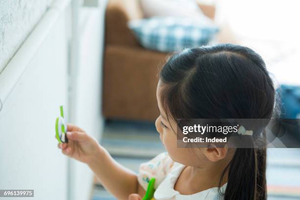 girl looking at alphabet magnet, side view - magnetwand stock-fotos und bilder