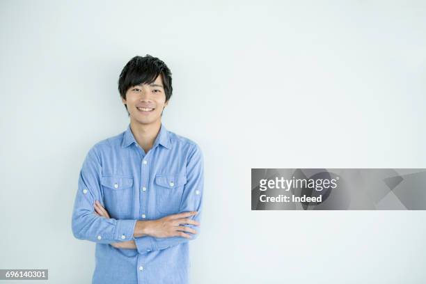 smiling young man with arms crossed - ventenne foto e immagini stock