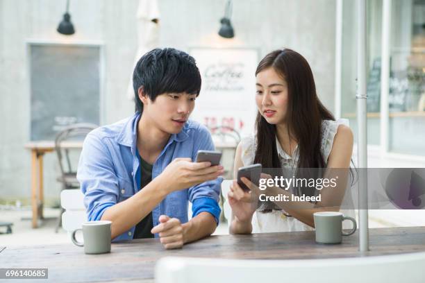 young couple using smart phone at cafe - coffee shop couple stock pictures, royalty-free photos & images