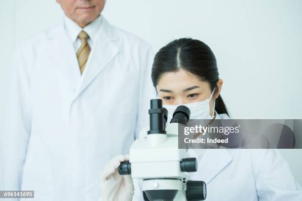 scientist using microscope and working at table - scientist standing next to table stock pictures, royalty-free photos & images