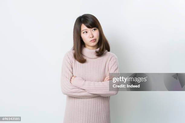 young woman crossing arms and thinking - confused white background stock-fotos und bilder