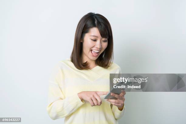 surprised woman looking at smart phone - front looking asian women stock pictures, royalty-free photos & images