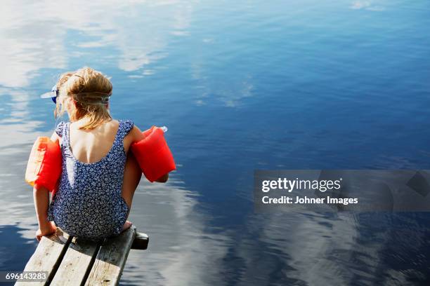 girl sitting on jetty in water wings - bathing jetty stock pictures, royalty-free photos & images