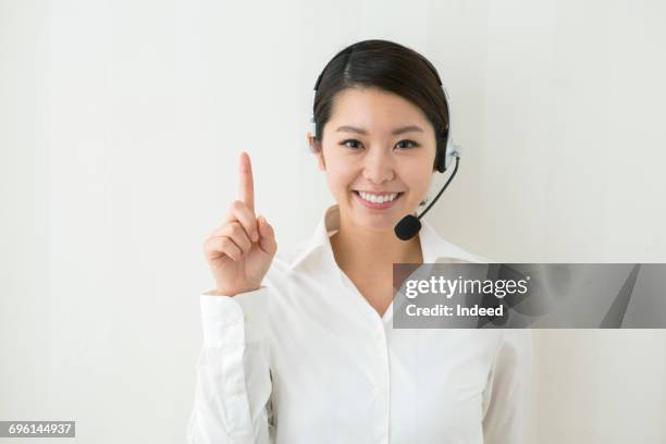 young woman with headset pointing with her finger - 人差し指 女性 ストックフォトと画像