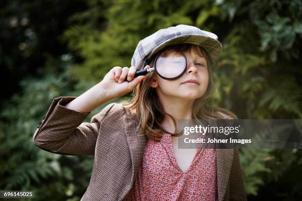 portrait of girl looking through magnifying glass - détective photos et images de collection