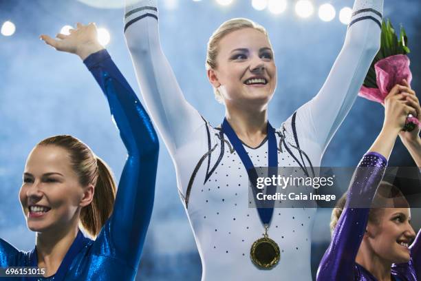 female gymnasts celebrating victory waving on winners podium - honors awards 2016 show stock pictures, royalty-free photos & images