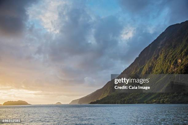 tranquil ocean and cliff, doubtful sound, south island new zealand - doubtful sound stock-fotos und bilder