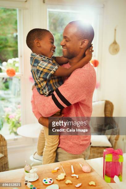 affectionate father and son hugging next to easter decorations - leanintogether stock pictures, royalty-free photos & images