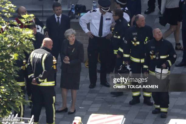 British Prime Minister Theresa May meeets firefighters as she visits the remains of Grenfell Tower, a residential tower block in west London which...