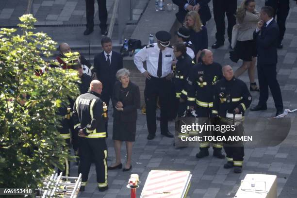 British Prime Minister Theresa May meeets firefighters as she visits the remains of Grenfell Tower, a residential tower block in west London which...