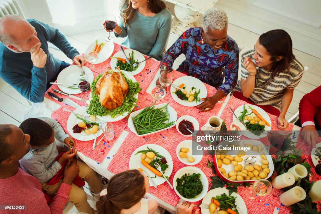 Overhead view multi-ethnic multi-generation family enjoying Christmas dinner at table