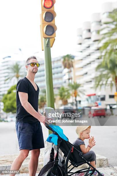 mid-adult man with son in baby stroller waiting - car red light stock pictures, royalty-free photos & images