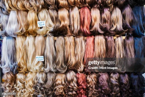 a display of hair extensions and hair pieces of different colours. - toupee stockfoto's en -beelden