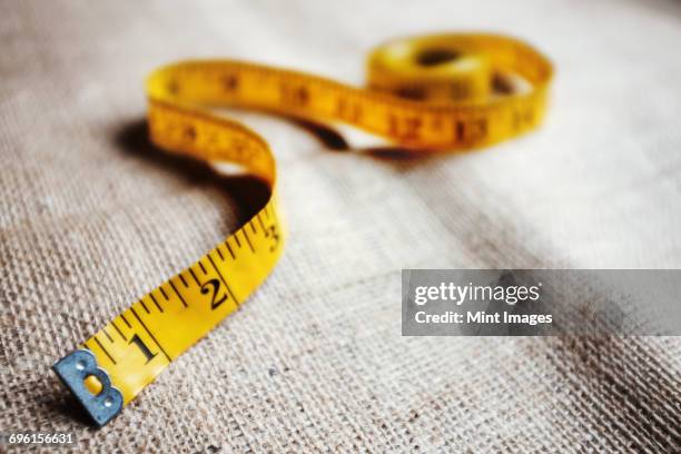 upholstery workshop. neutral coloured folded furnishing fabric and a yellow tape measure. - furniture stock pictures, royalty-free photos & images