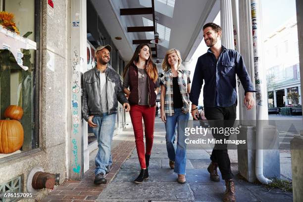 two young men and two young women walking along a sidewalk, smiling. - four people holding hands stock pictures, royalty-free photos & images