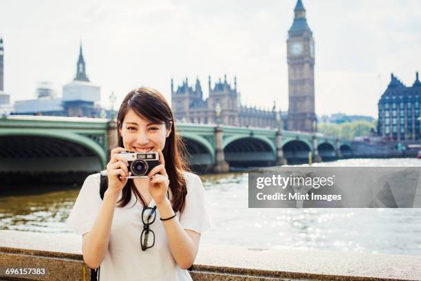 young japanese woman enjoying a day out in london, standing on the queens walk by the river thames. - london tourist stock pictures, royalty-free photos & images