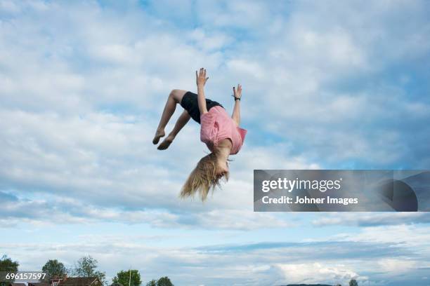 girl doing somersault mid-air - trampoline stock-fotos und bilder