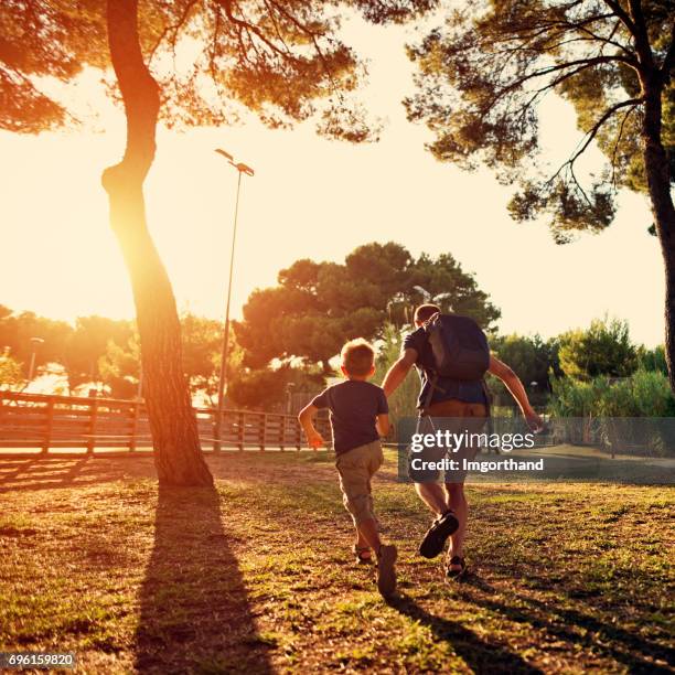 père et fils courir dans le parc de la ville - dos humain photos et images de collection