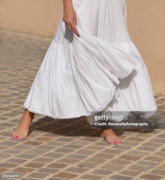 barefoot woman holding hem of her dress - hem foto e immagini stock