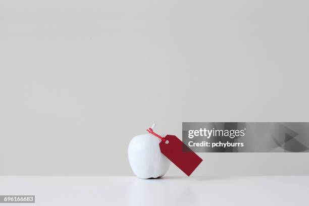 white painted apple with red tag - pchyburrs stock pictures, royalty-free photos & images