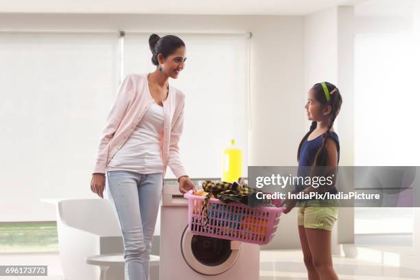 mother and little daughter carrying laundry basket together - laundry basket stock pictures, royalty-free photos & images