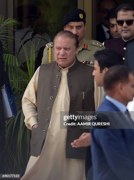 Pakistan's Prime Minister Nawaz Sharif is escorted by security personnel as he leaves after appearing before an anti-corruption commission at the...